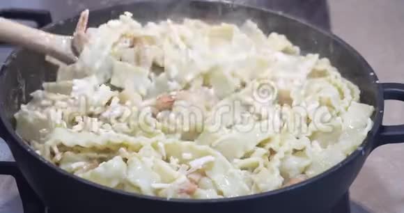 一位女士将意大利面食马法丁和虾蒜帕尔马干酪和调味料混合在锅里视频的预览图