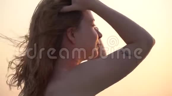 日落时靠近一位年轻女子在海滩上摆姿势视频的预览图