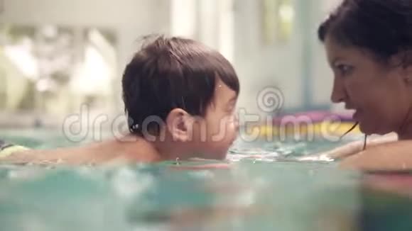一个年轻的黑发女人教她的孩子潜入水中在游泳池里游泳母亲和儿子在游泳视频的预览图