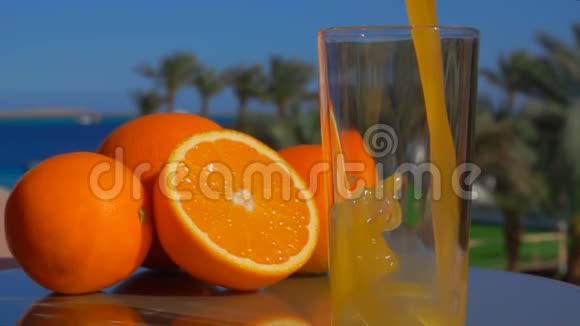 在海洋景观的背景下新鲜的橙汁倒入玻璃杯中视频的预览图