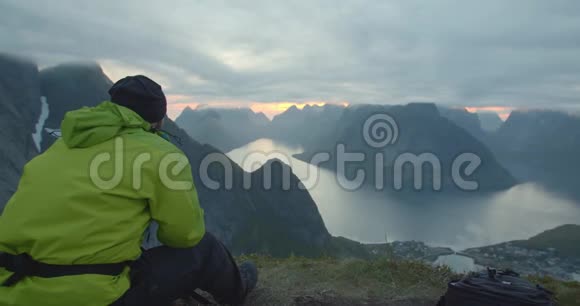 旅行者坐在美丽的挪威峡湾的山上视频的预览图