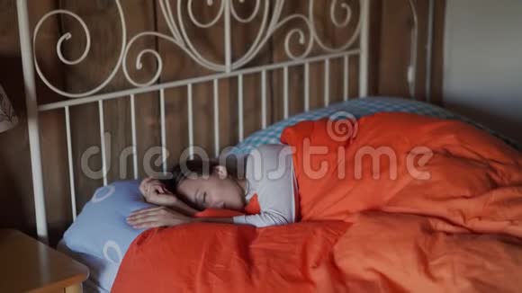 美丽的年轻女子在卧室里醒来睡觉时间彩色床上用品视频的预览图