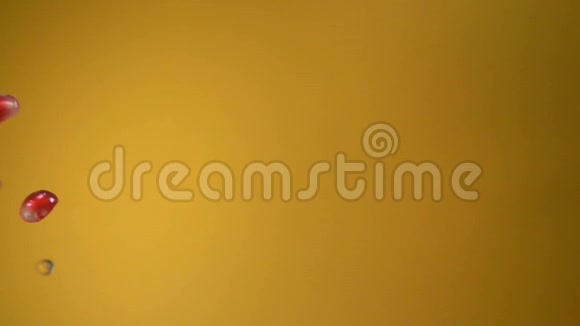 石榴汁颗粒斜落在黄色背景上视频的预览图