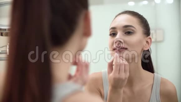 化妆女人在浴室的唇上涂抹液体唇膏视频的预览图