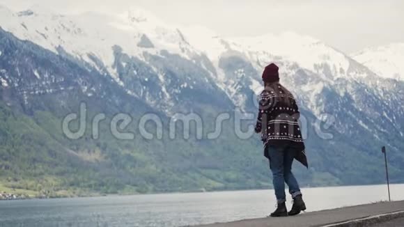 穿着花纹外套和针织帽子的女人在湖边用面包喂鸟视频的预览图