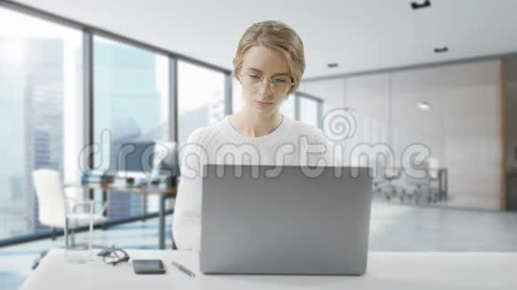 女人坐在办公桌前用笔记本电脑年轻的欧洲女商人正坐在办公室里工作视频的预览图