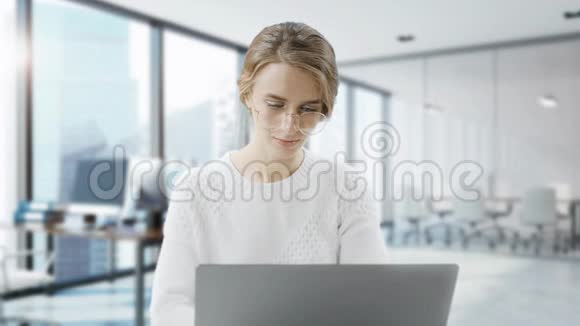 女人坐在办公桌前用笔记本电脑年轻的欧洲女商人正坐在办公室里工作视频的预览图