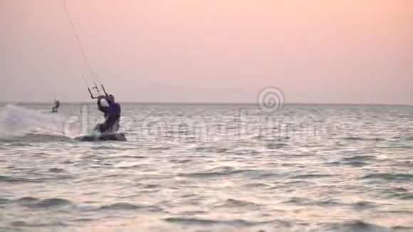 日落时分在海边冲浪者在空中表演特技表演视频的预览图