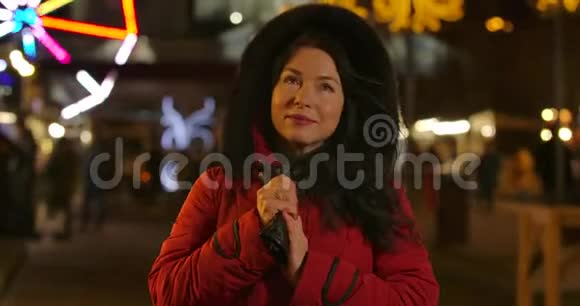 站在城市市场上的成年黑发白人妇女的肖像一位身穿红色外套的中年女士手拿手套视频的预览图