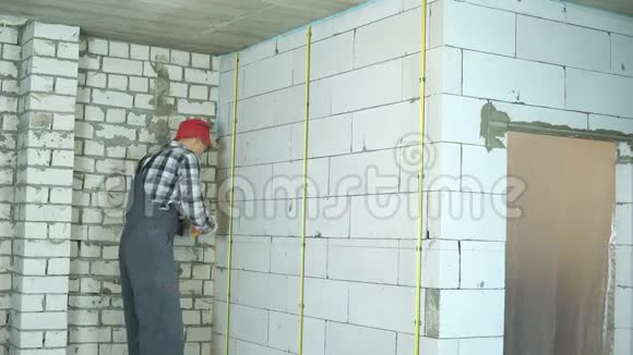 青年建筑工人在加气混凝土砌块墙上安装金属栏杆视频的预览图