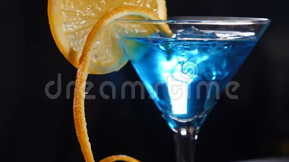 优美慢动作饮料视频中慢动作黑色蓝色鸡尾酒上的橙片特写镜头视频的预览图