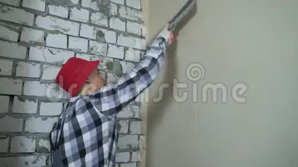 年轻建筑工人在施工现场将抹灰墙压平视频的预览图