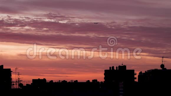飞机正飞越城市屋顶夕阳与橙色和粉红色的天空在背景视频的预览图