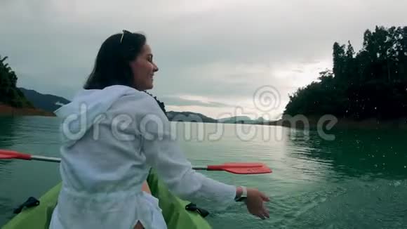 微笑的女士坐在皮艇上时正在溅水视频的预览图