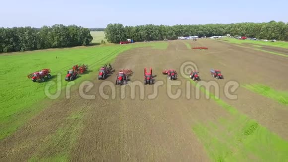 在阳光明媚的日子里农场机器在绿色的田野上排队视频的预览图