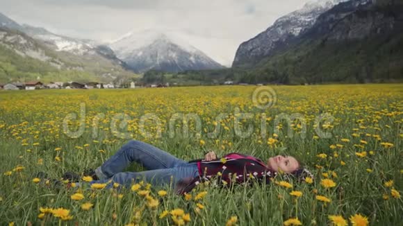 年轻的美女在瑞士阿尔卑斯山的背景下在花田里放松视频的预览图