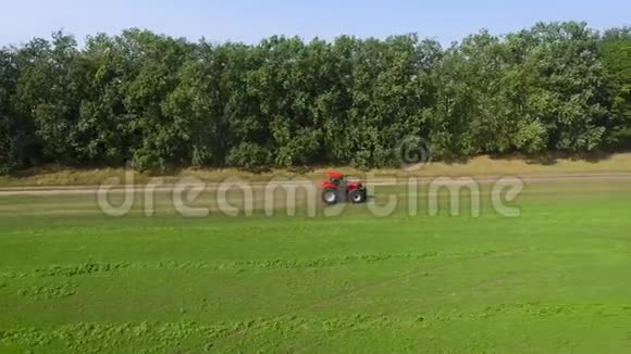 红色拖拉机骑在乡间的绿野上视频的预览图