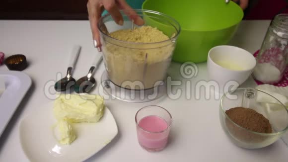 一个女人把从搅拌碗里倒出来的碎饼干倒进一个容器里其他制作土豆曲奇的原料也列了出来视频的预览图
