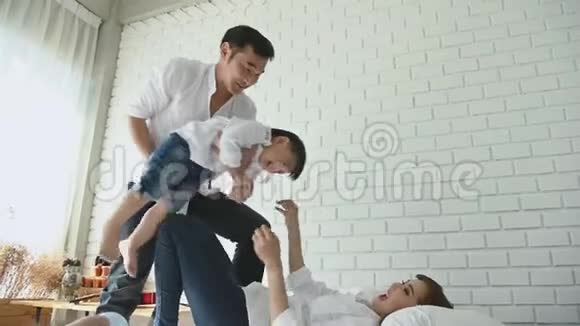 父母在家里的卧室里和一个半日本男孩玩飞机幸福的家庭和宝宝概念多种疗法视频的预览图