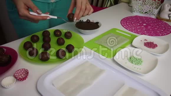 一个女人把海绵蛋糕上的球浸到巧克力里做一个土豆蛋糕盘子旁边有蛋糕液体巧克力和视频的预览图