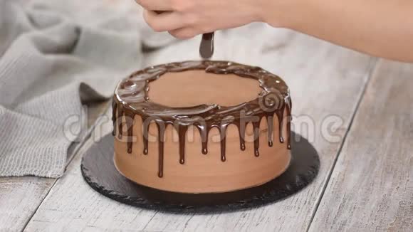 玻璃巧克力蛋糕与融化的巧克力女人把巧克力倒在蛋糕上自制可可分层蛋糕视频的预览图