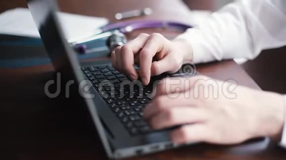 身穿白大褂的无名男医生正在笔记本电脑旁工作从上面看视频的预览图