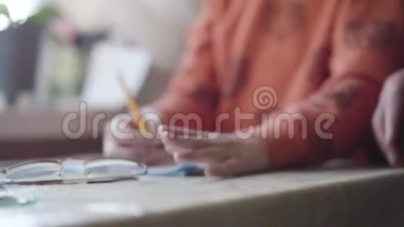 桌子上躺着一副眼镜像一个模糊的白种人小男孩用铅笔坐在桌子旁村视频的预览图