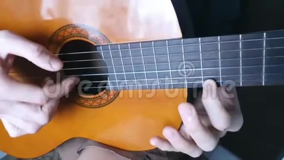 浅棕色吉他上的琴弦的枚举在演奏乐器男人手视频的预览图