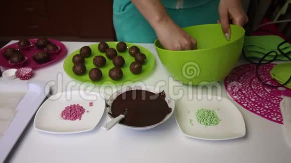 女人做土豆蛋糕放大工作表面盘子旁边是蛋糕液体巧克力和彩色洒视频的预览图