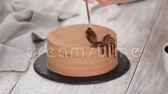 玻璃巧克力蛋糕与融化的巧克力女人把巧克力倒在蛋糕上自制可可分层蛋糕视频的预览图