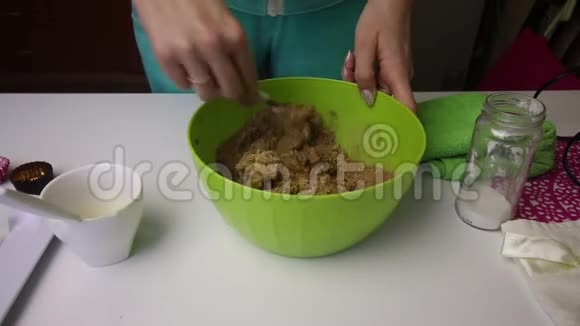 一个女人把饼干碎屑可可和黄油混合在一个容器里准备一大堆饼干土豆视频的预览图