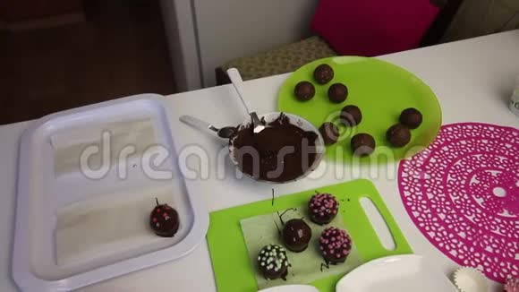 在工作表面是巧克力海绵蛋糕球上面还有花洒蛋糕用的小块土豆在盘子旁边视频的预览图