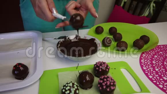 一个女人把一个巧克力海绵球放在表面做土豆蛋糕盘子旁边有蛋糕液体巧克力和视频的预览图