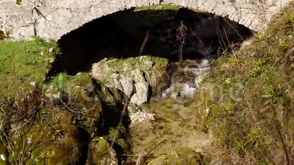 一座古老的岩石桥穿过一条小溪视频的预览图