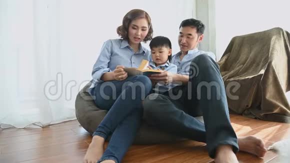 父母带着半日本男孩一起在家里的卧室看书幸福的家庭和宝宝概念多民族混血视频的预览图