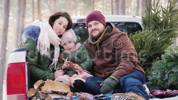 一个幸福的年轻家庭正在为圣诞节的早晨做准备在购买成功后坐在车后视频的预览图