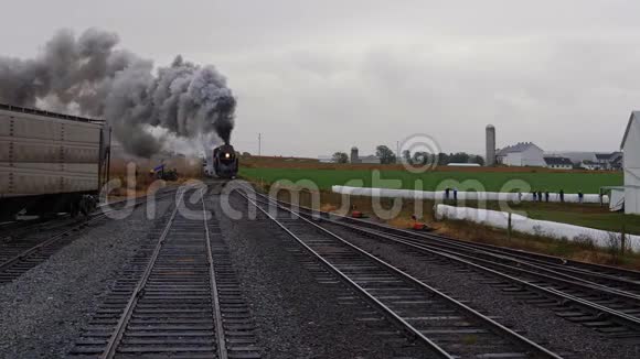一辆蒸汽机车拉运车驶进有烟和蒸汽的车场视频的预览图