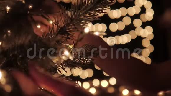 女人在圣诞树上装饰灯光背景是bokeh灯视频的预览图