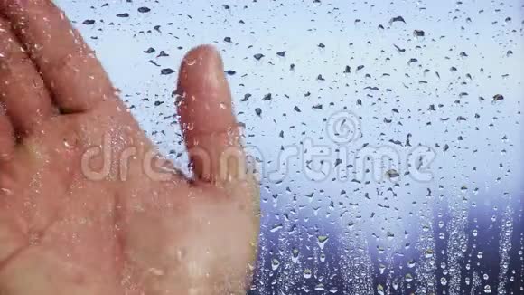 雨后手握在潮湿的窗户上背景模糊关门视频的预览图