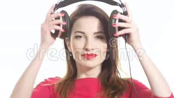 穿红衣服的女孩戴上大耳机开始对着音乐摇摆在白色背景下跳舞和接吻视频的预览图