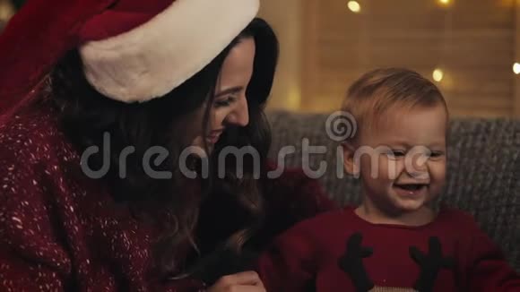 亲近圣诞老人帽里微笑的白种人妈妈和她可爱的可爱的孩子家庭假期和新年的概念视频的预览图