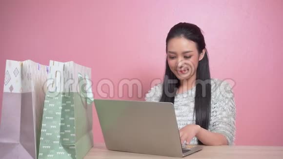 美女亚洲女人用笔记本上网购物视频的预览图