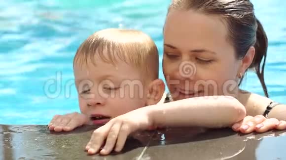 妈妈和儿子在游泳池里休息泳池里的母子肖像视频的预览图