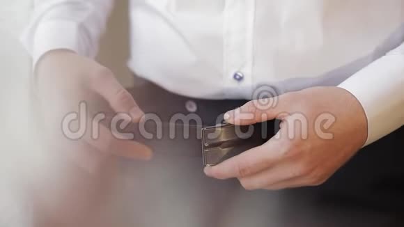 新郎系着腰带一个穿白衬衫的男人在婚礼的早晨把腰带系在裤子上视频的预览图