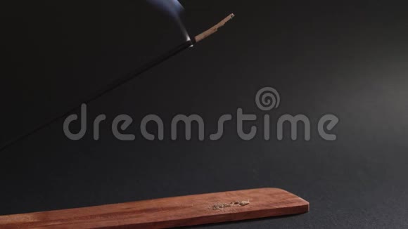 东方芳香烟雾香棒在黑色背景的木架上燃烧自然烟雾上升视频的预览图