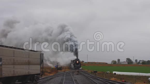 一辆蒸汽机车拉运车驶进有烟和蒸汽的车场视频的预览图