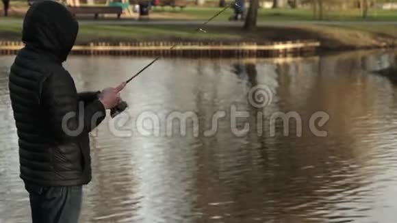 初春的渔夫一个鱼人在城市公园里用勺子钓鱼视频的预览图