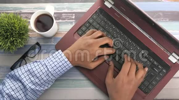 男子在桌上的笔记本电脑上打字的俯视图视频的预览图