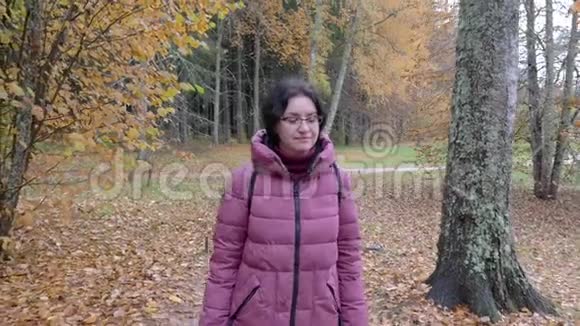 乌云密布的秋日白种人女人在公园散步停下来看远处视频的预览图