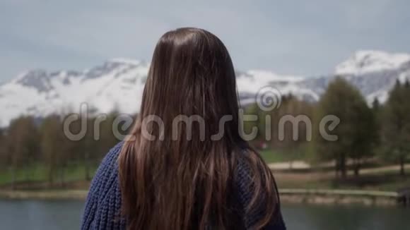 长发黑发女人站着看着瑞士山湖的风景后景浮动重点视频的预览图